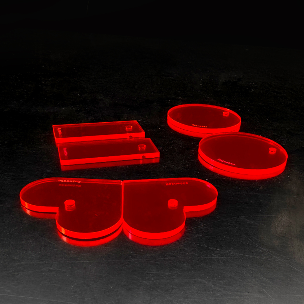 Charms plexi fluo rouge, formes cœur et rond, illuminés sous UV dans le noir