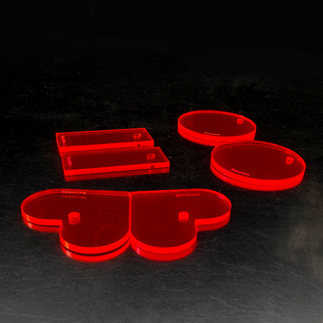 Charms plexi fluo rouge, formes cœur et rond, illuminés sous UV dans le noir Immagine